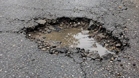 Foto de un bache con agua en el asfalto